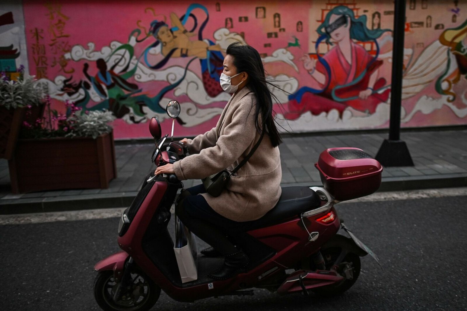 Una mujer con mascarilla monta en moto