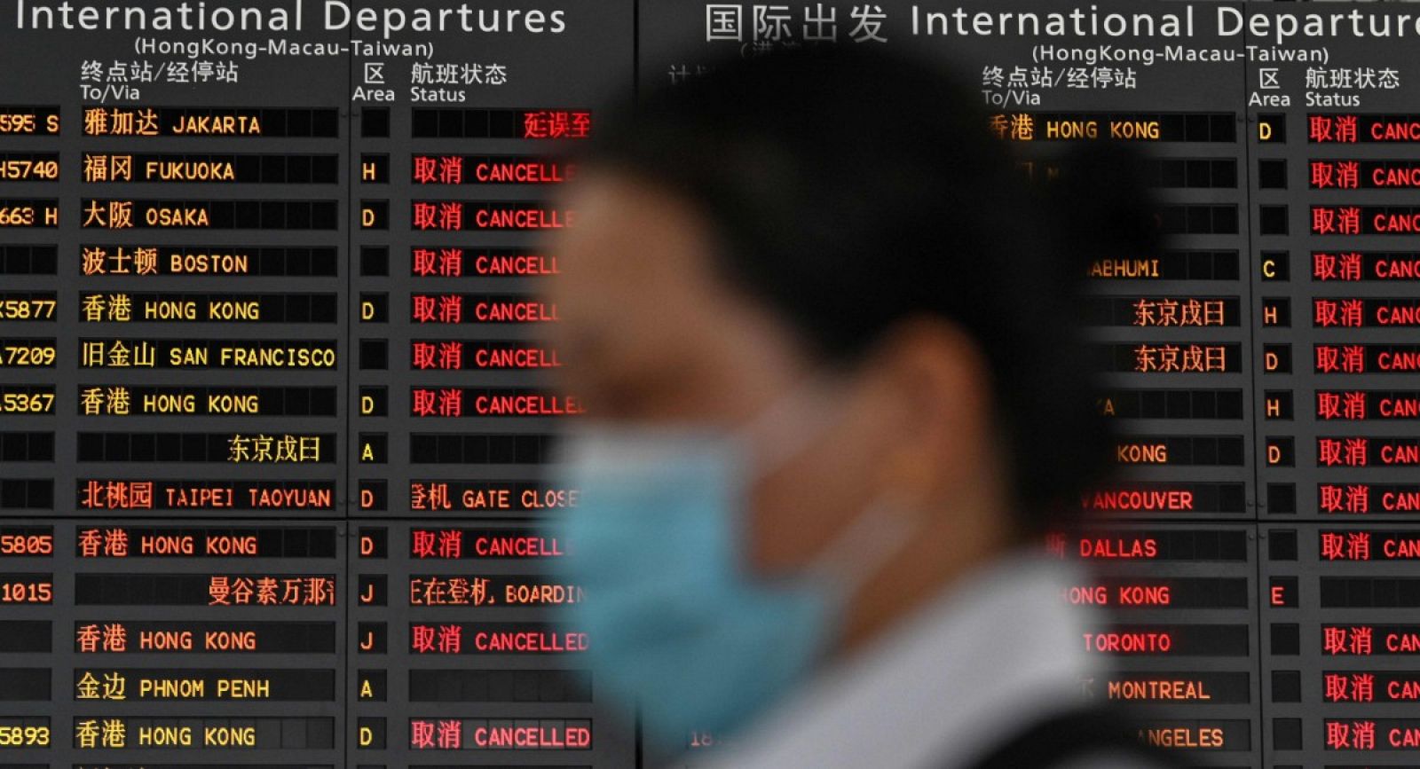 Una mujer con mascarilla espera en el aeropuerto de Shanghái