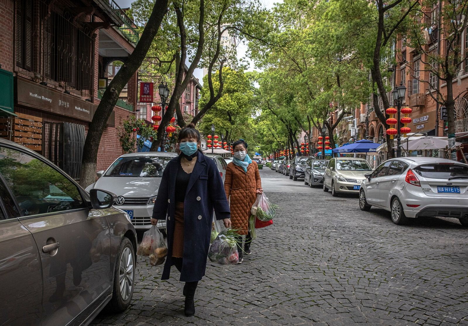 Dos mujeres llevan las bolsas de la compra en las calles de Wuhan