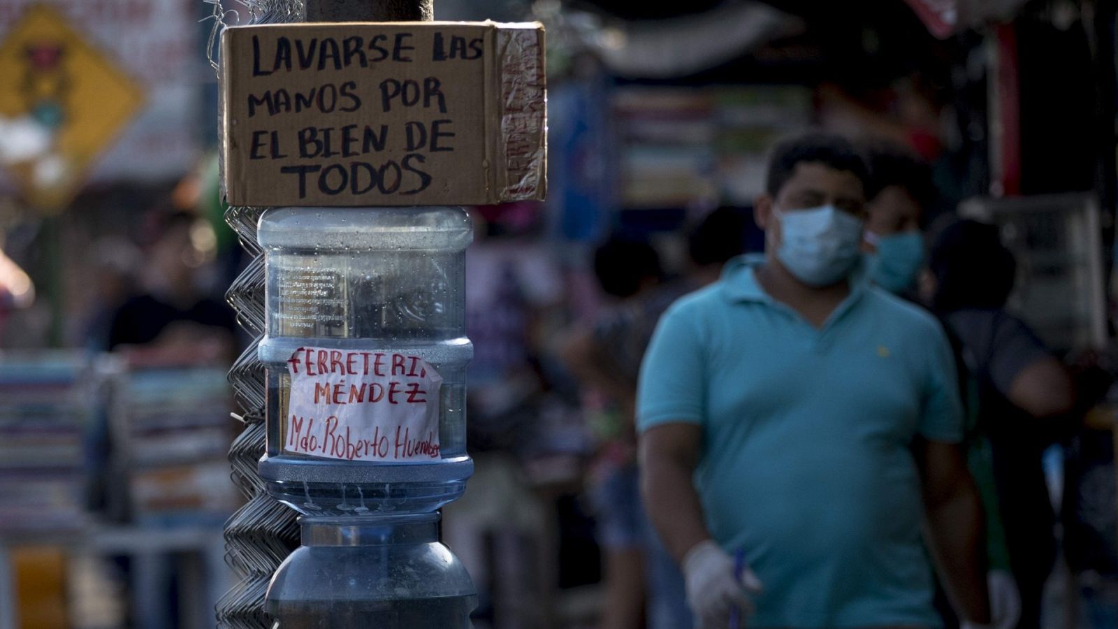 Un hombre con un mascarilla y guantes camina  junto a un tanque con agua del mercado Roberto Huembes en Managua