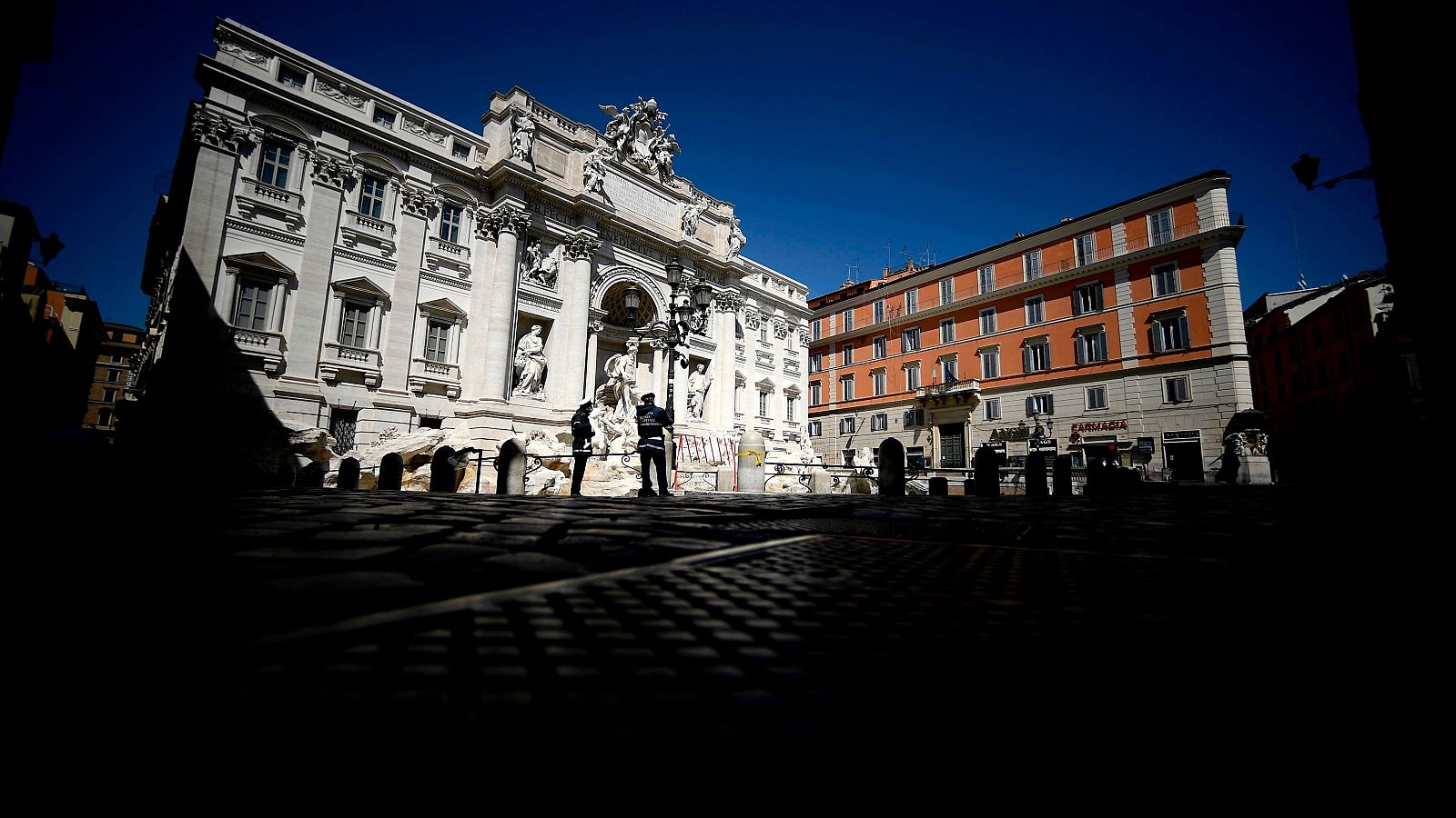 Coronavirus en Italia: Agentes de policía patrullan en una desierta Fontana de Trevi, en Roma.