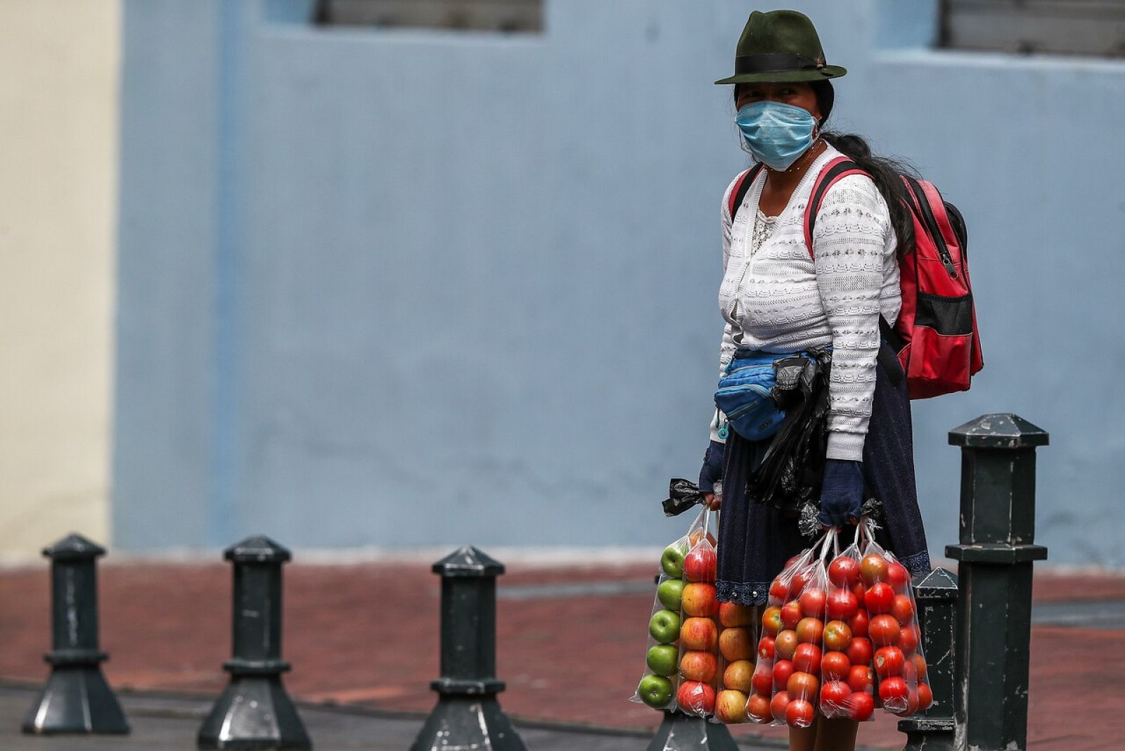 Una mujer con mascarilla vendiendo fruta en una calle de Quito, Perú.