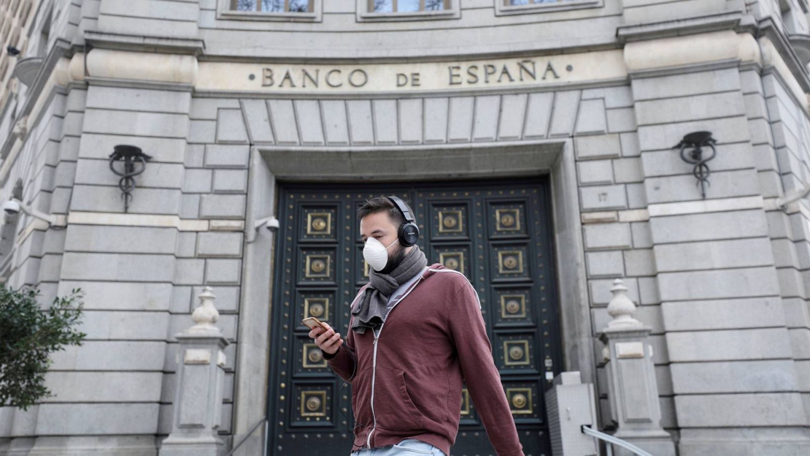 Un hombre con mascarilla junto a la sede del Banco de España en Madrid