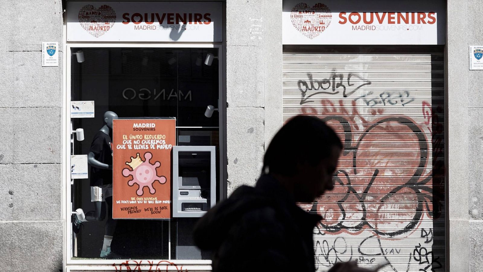 Una persona pasa delante de un establecimiento cerrado durante el estado de alarma en Madrid por la pandemia del coronavirus
