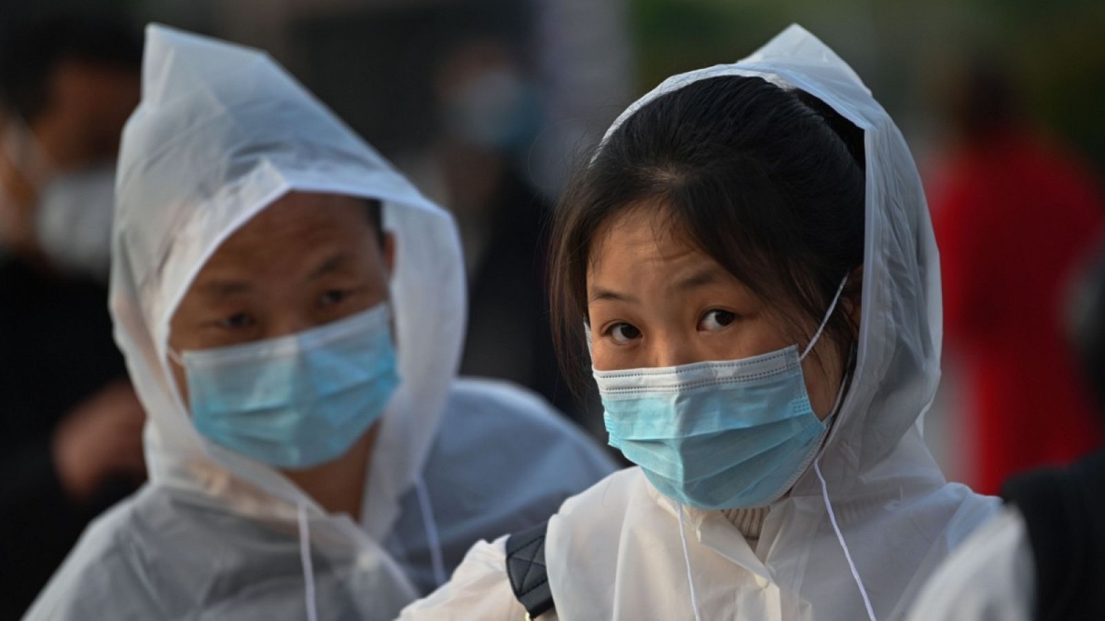 Una pareja con ropa protectora y mascarillas esperando en la estación de tren de Hankou en Wuhan.