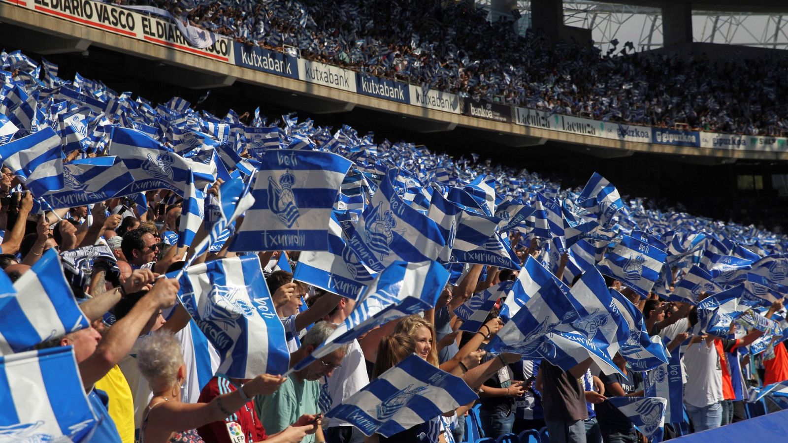 El público agita banderas blanquiazules en la grada del estadio de Anoeta.