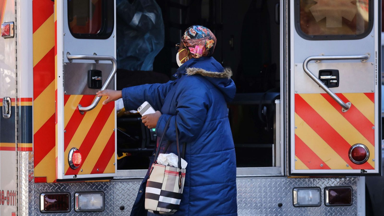 Una mujer acompaña a un paciente, trasladado en ambulancia en el barrio de Brooklyn, en Nueva York