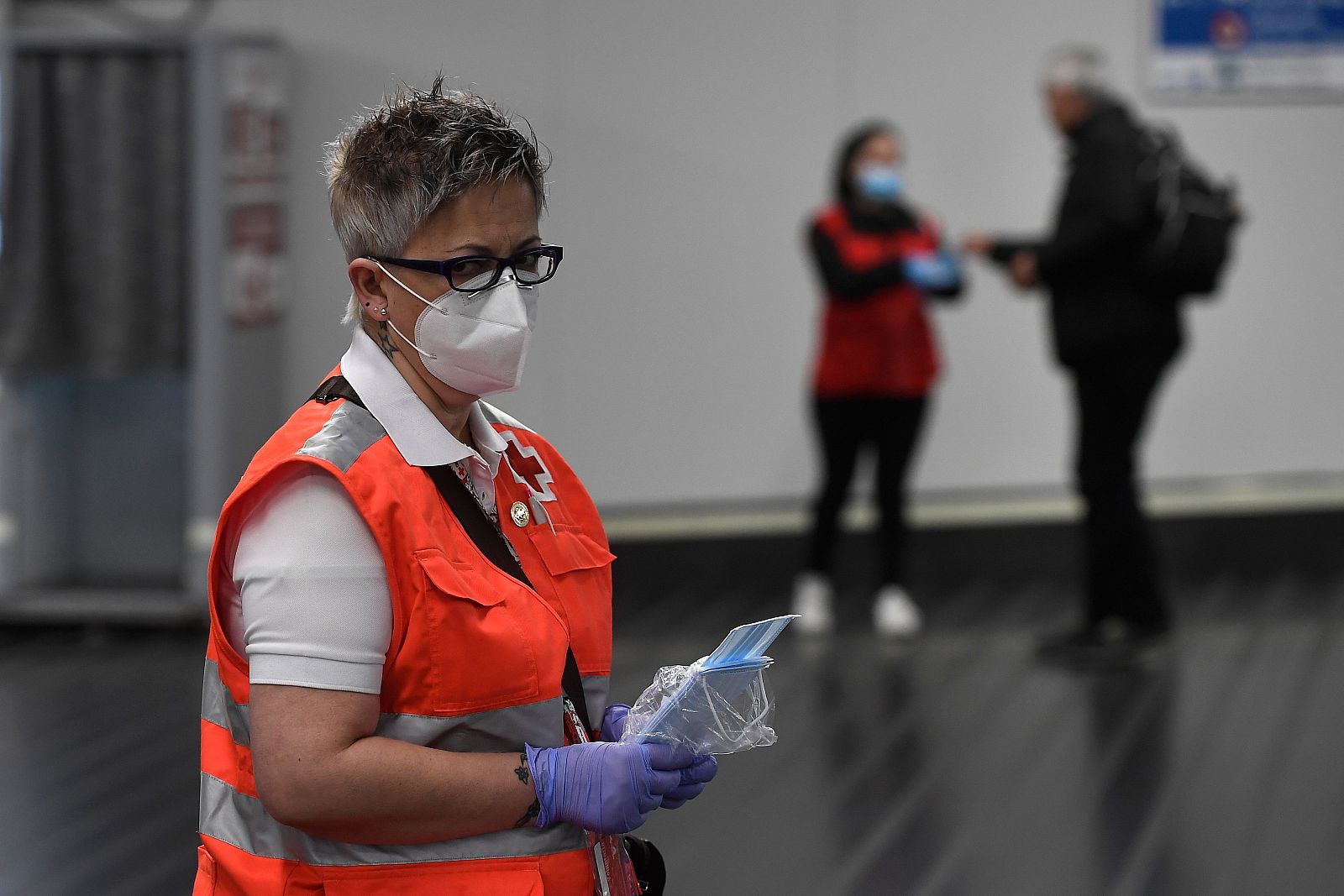 Un voluntario de la Cruz Roja distribuye mascaras faciales en la estación de Chamartín de Madrid.