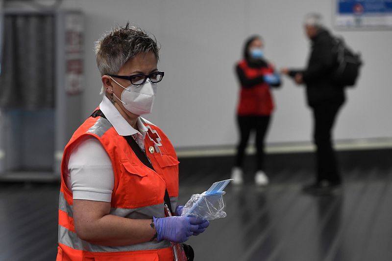 Un voluntario de la Cruz Roja distribuye mascaras faciales en la estación de Chamartín de Madrid.