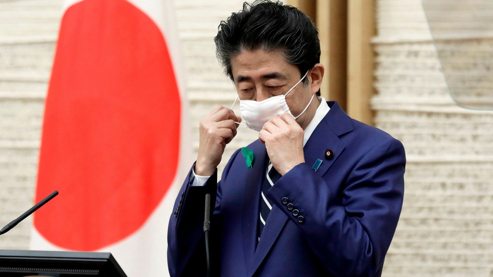 El primer ministro de Japón, Shinzo Abe, se quita la máscara facial antes de la conferencia de prensa