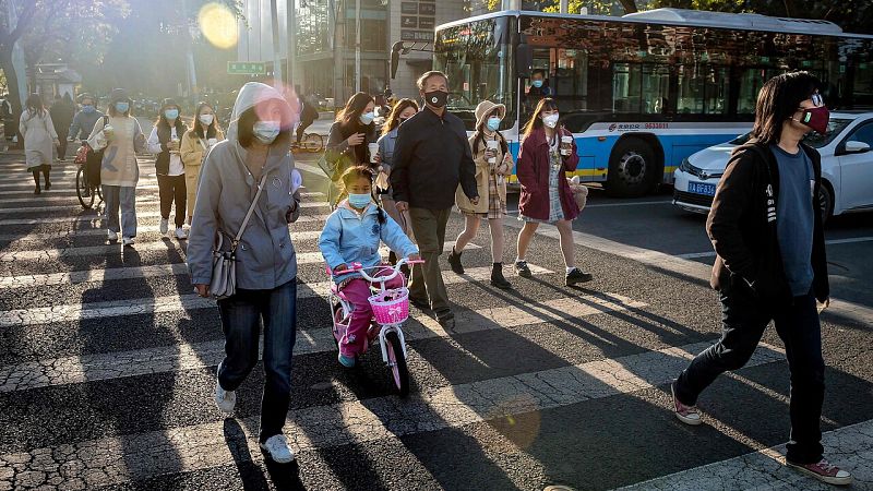 Un grupo de personas con mascarillas cruza la calle en Pekín
