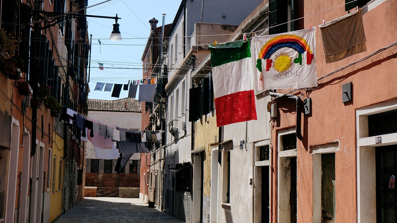 Coronavirus en Italia: Una bandera italiana y una pancarta con el lema "Todo irá bien" cuelgan de un edificio en una calle vacía de Venecia.