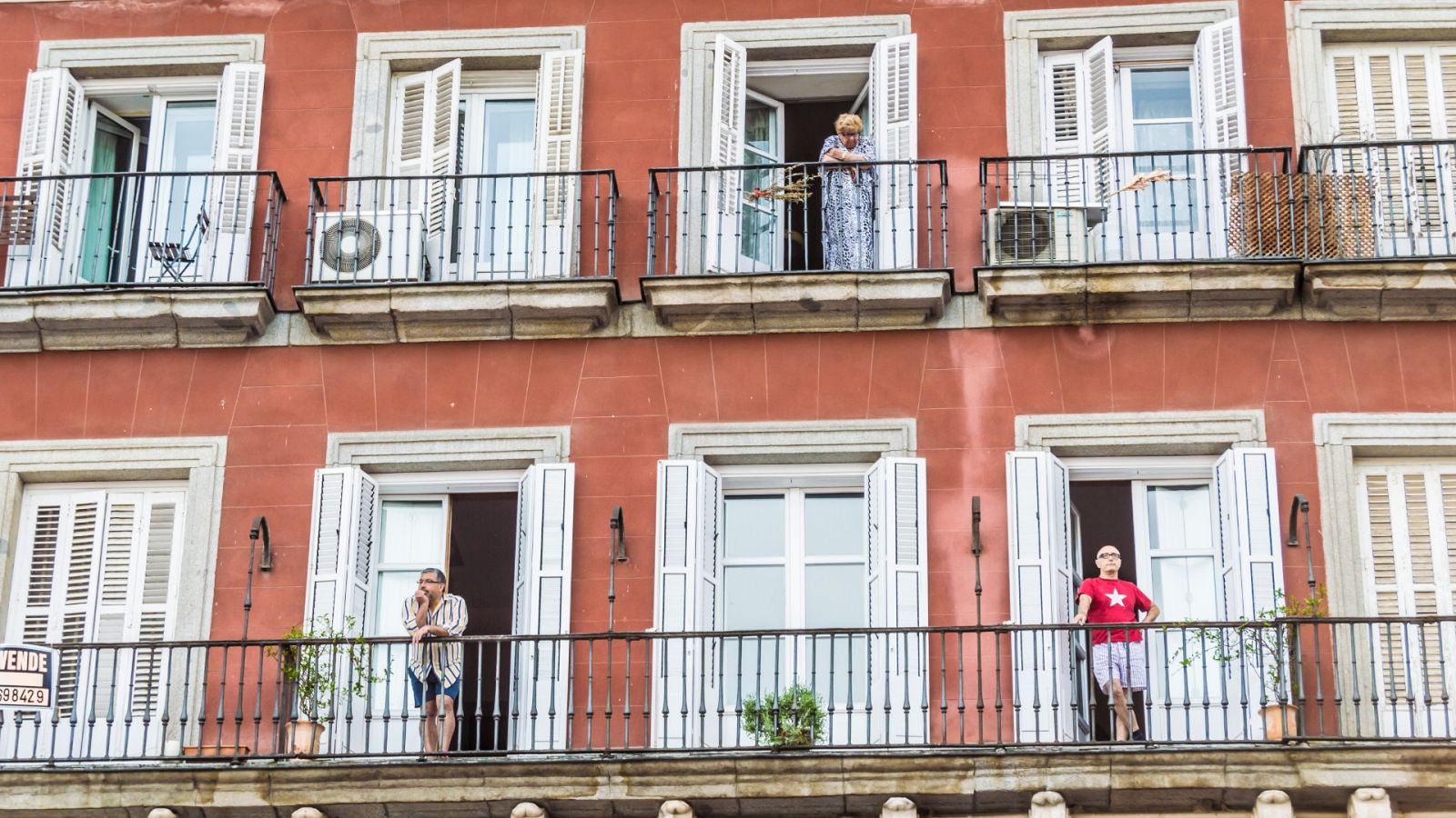 Varios vecinos se asoman a los balcones en un edificio de Madrid