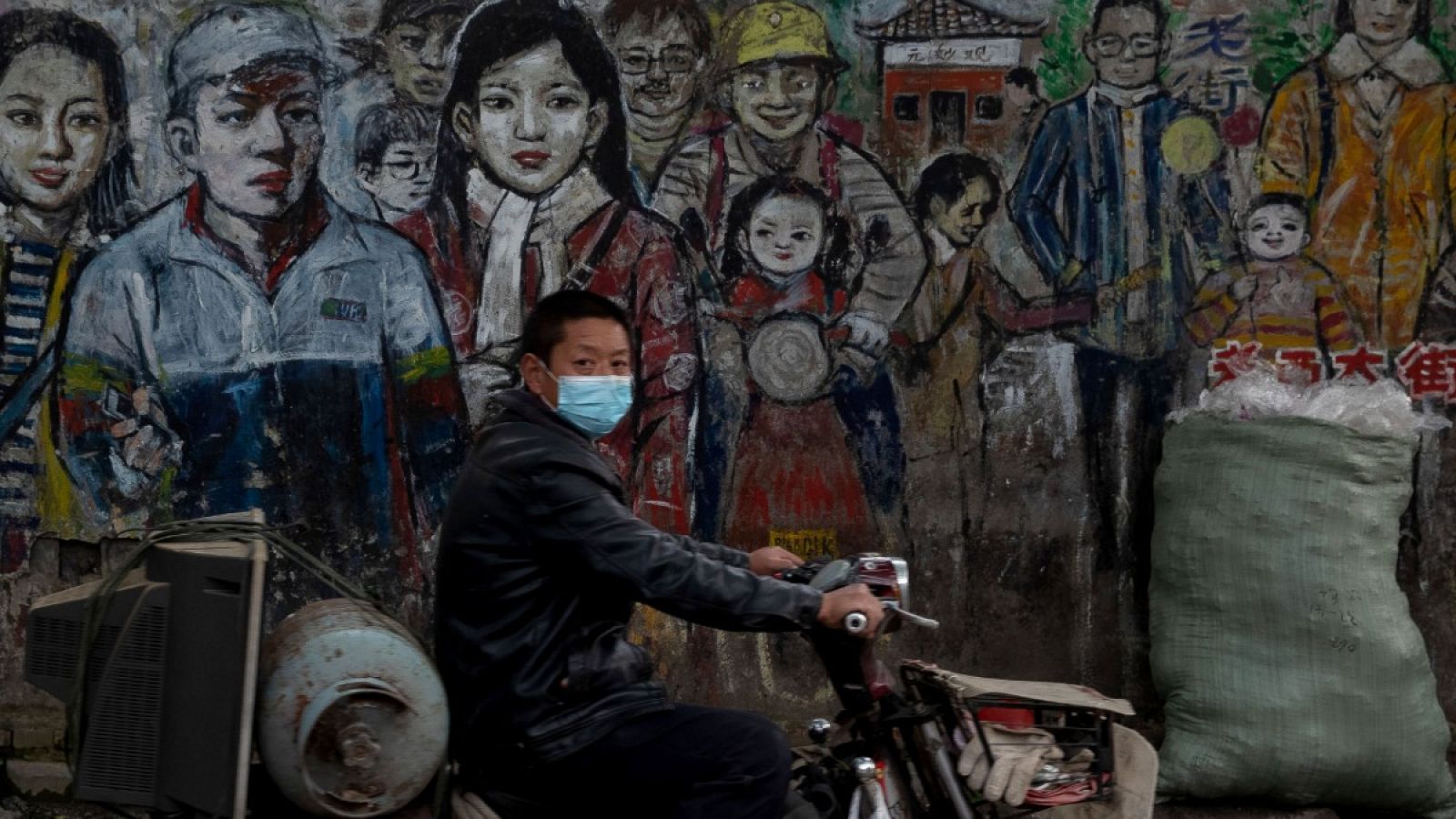 Un hombre con mascarilla conduciendo su moto por una calle en Wuhan.