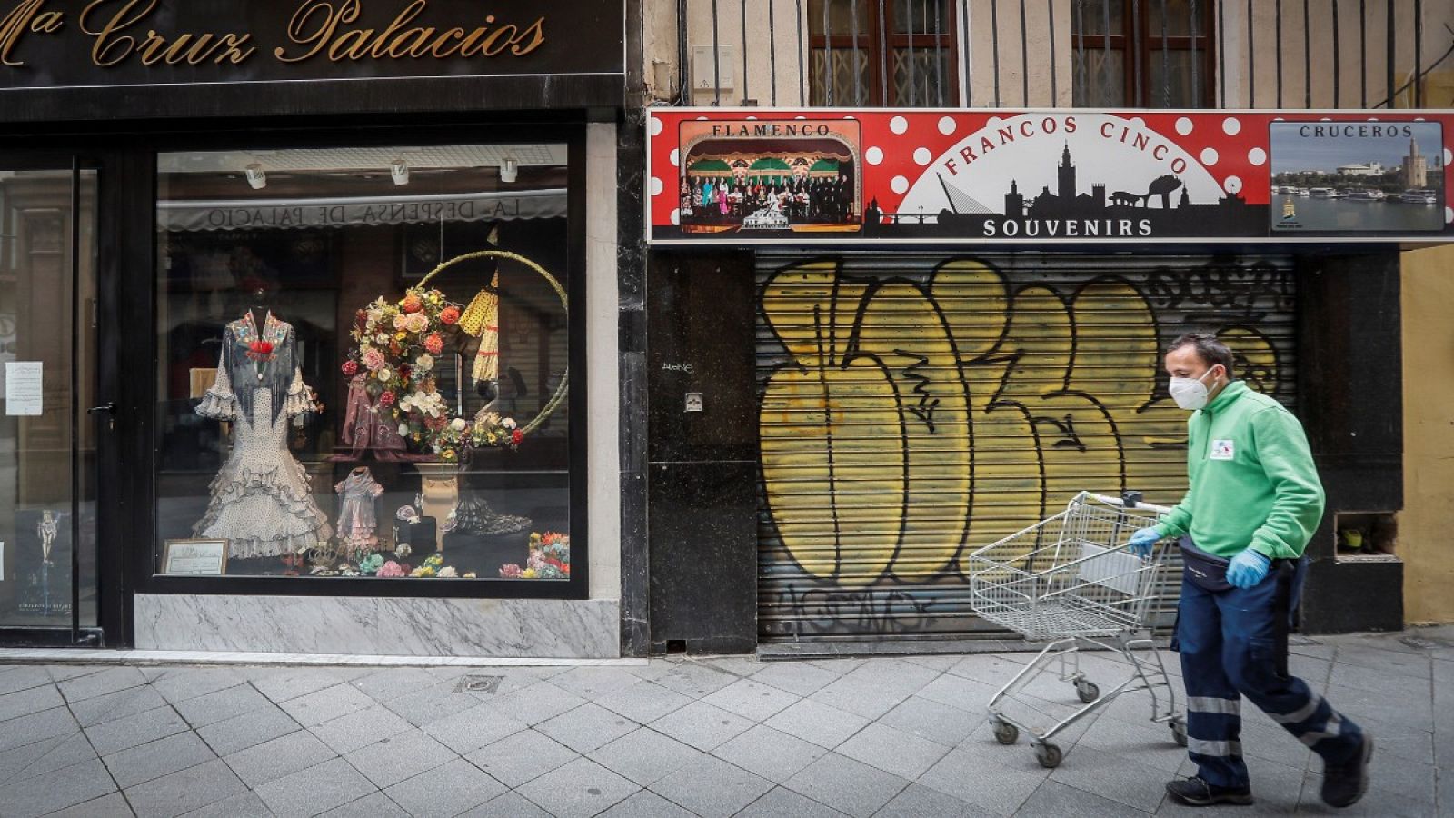 Un hombre camina junto a una tienda de trajes de flamenca cerrada en Sevilla