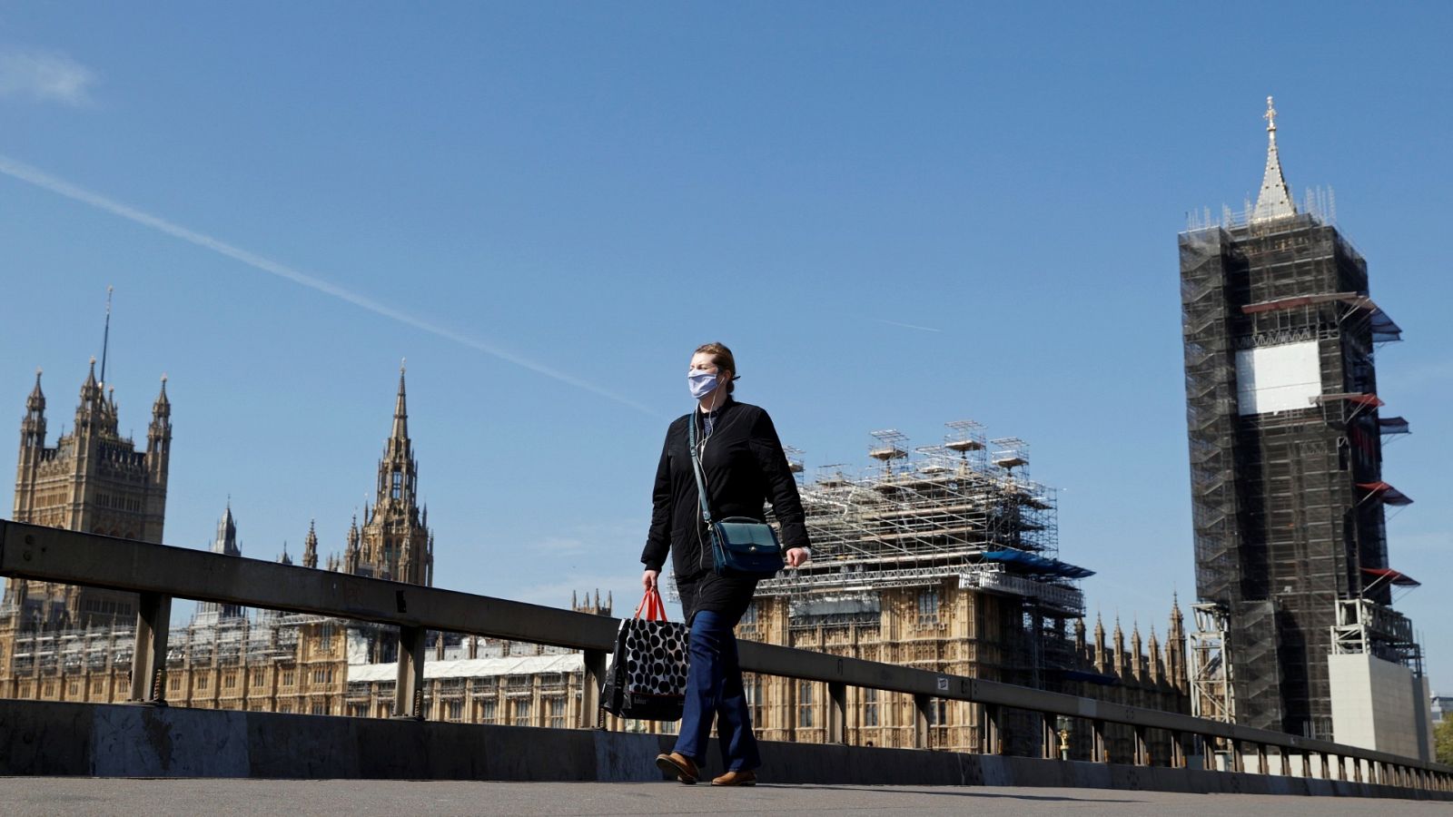 Una mujer con mascarilla camina por el puente de Westminster, en Londres.