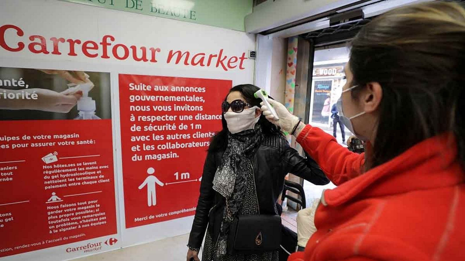 Personal de Carrefour toma la temperatura a una clienta en una de sus tiendas francófonas.