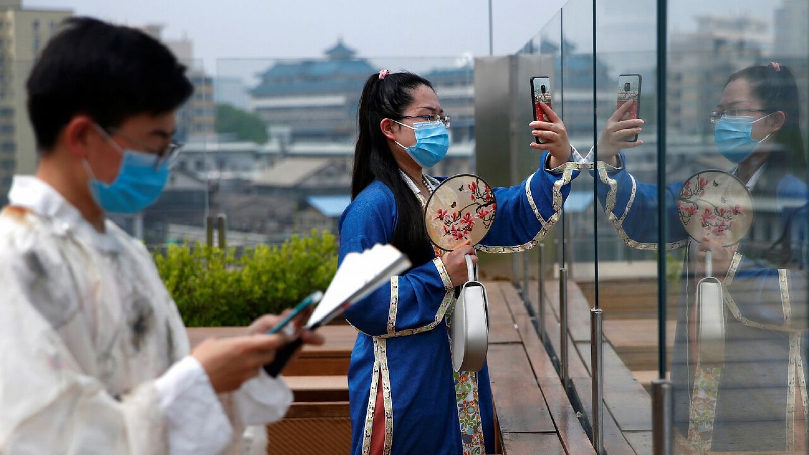 Clientes se toman fotos en una terraza de Pekín con trajes tradicionales chinos y mascarillas