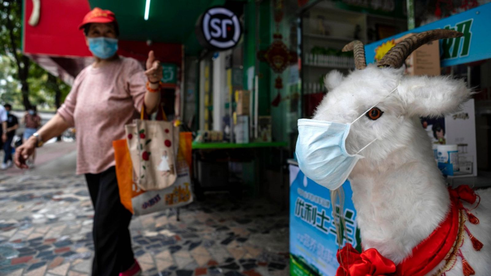 Una mujer con mascarilla paseando por un mercado en Guangzhou, China.