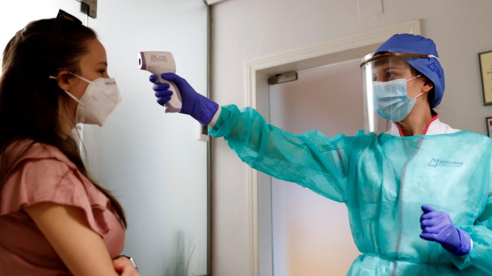 Una empleada de una clínica dental toma la temperatura a una clienta en Madrid