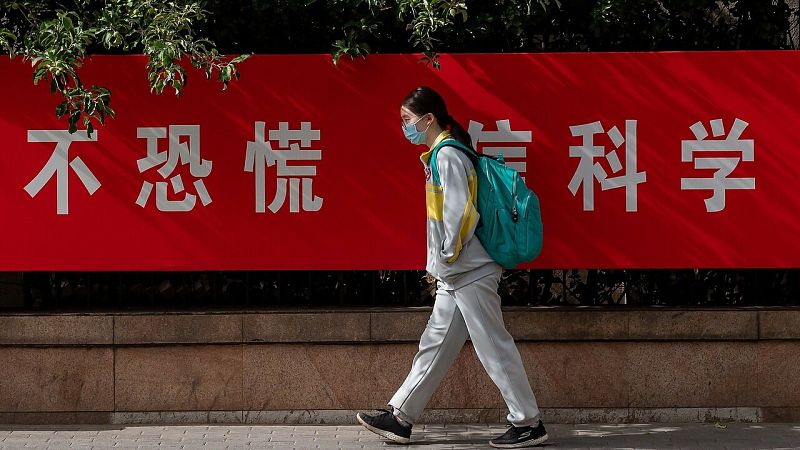 Una estudiante camina por una calle de Pekín