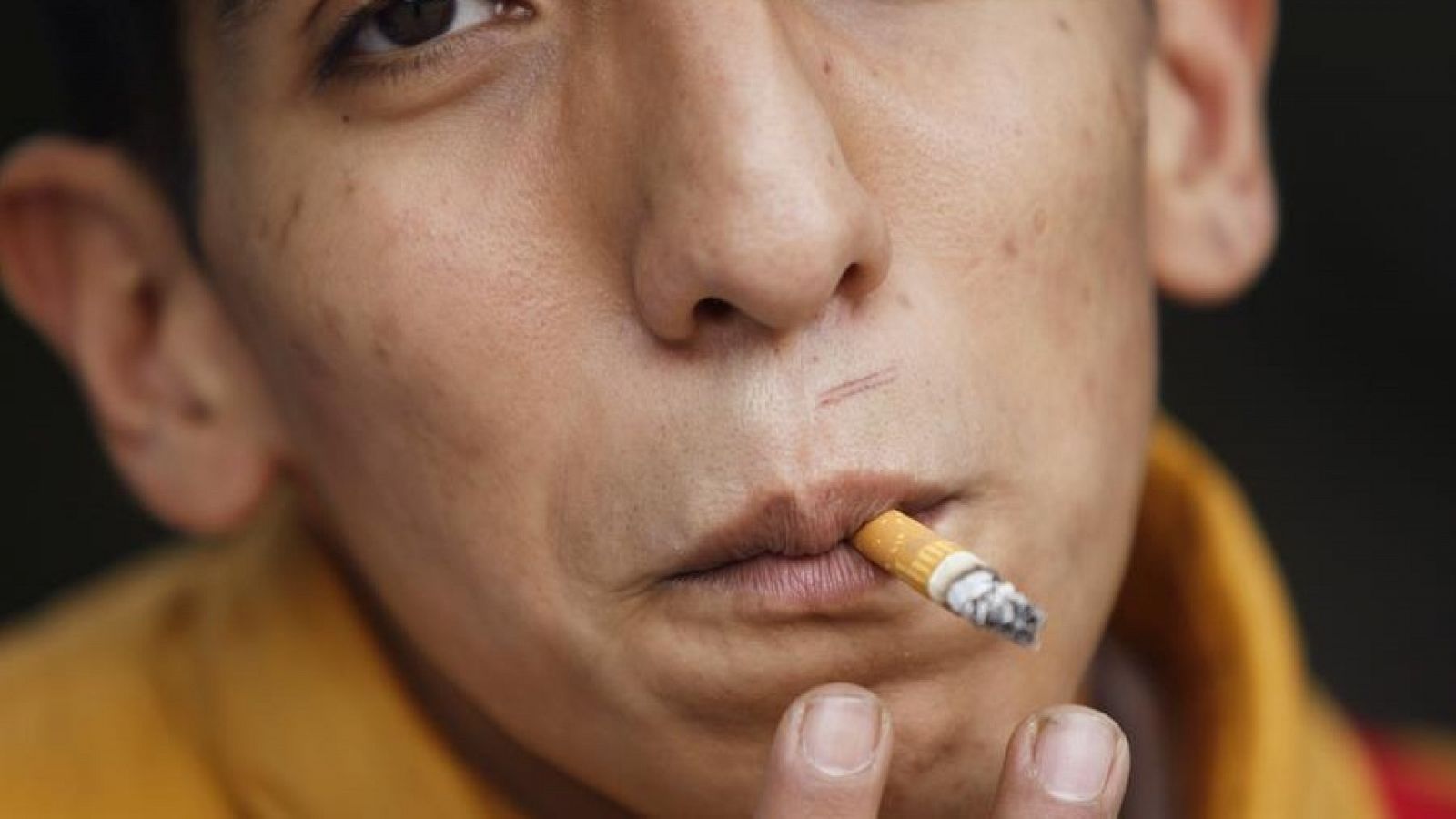 Un adolescente fumando un cigarrillo.