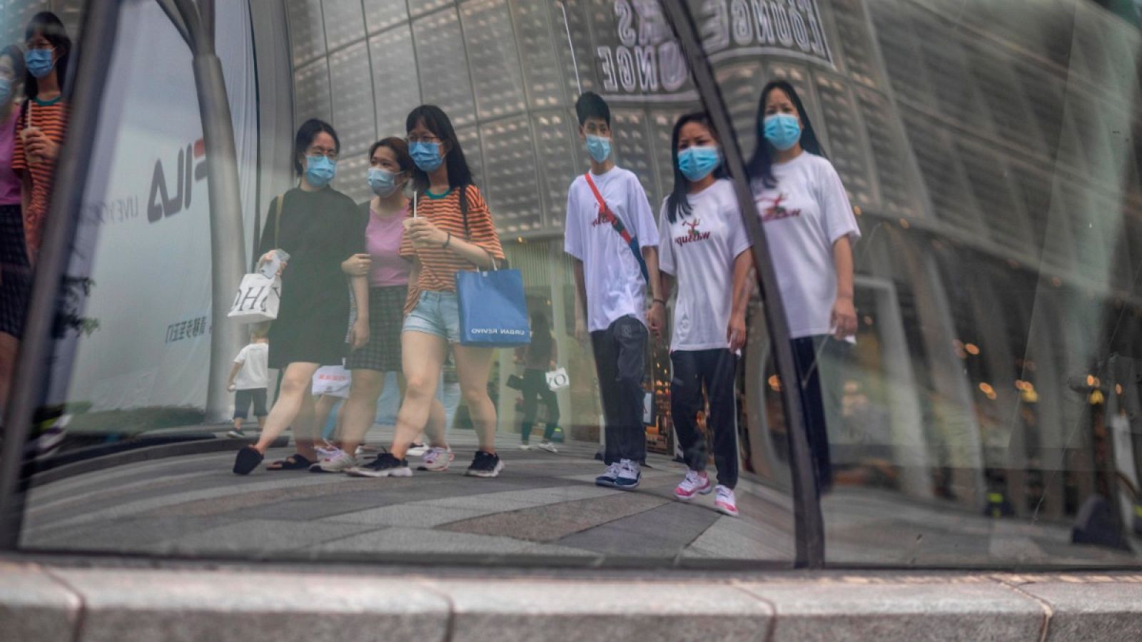 Gente reflejada en un escaparate mientras caminan por una calle en Guangzhou (Cantón), China.