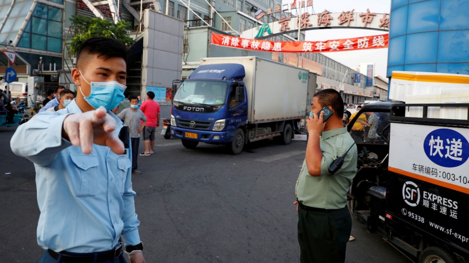 Guardias de seguridad con mascarillas controlan el exterior del mercado que ha sido cerrado después de que se detectaran nuevos contagios de coronavirus en Pekín, China