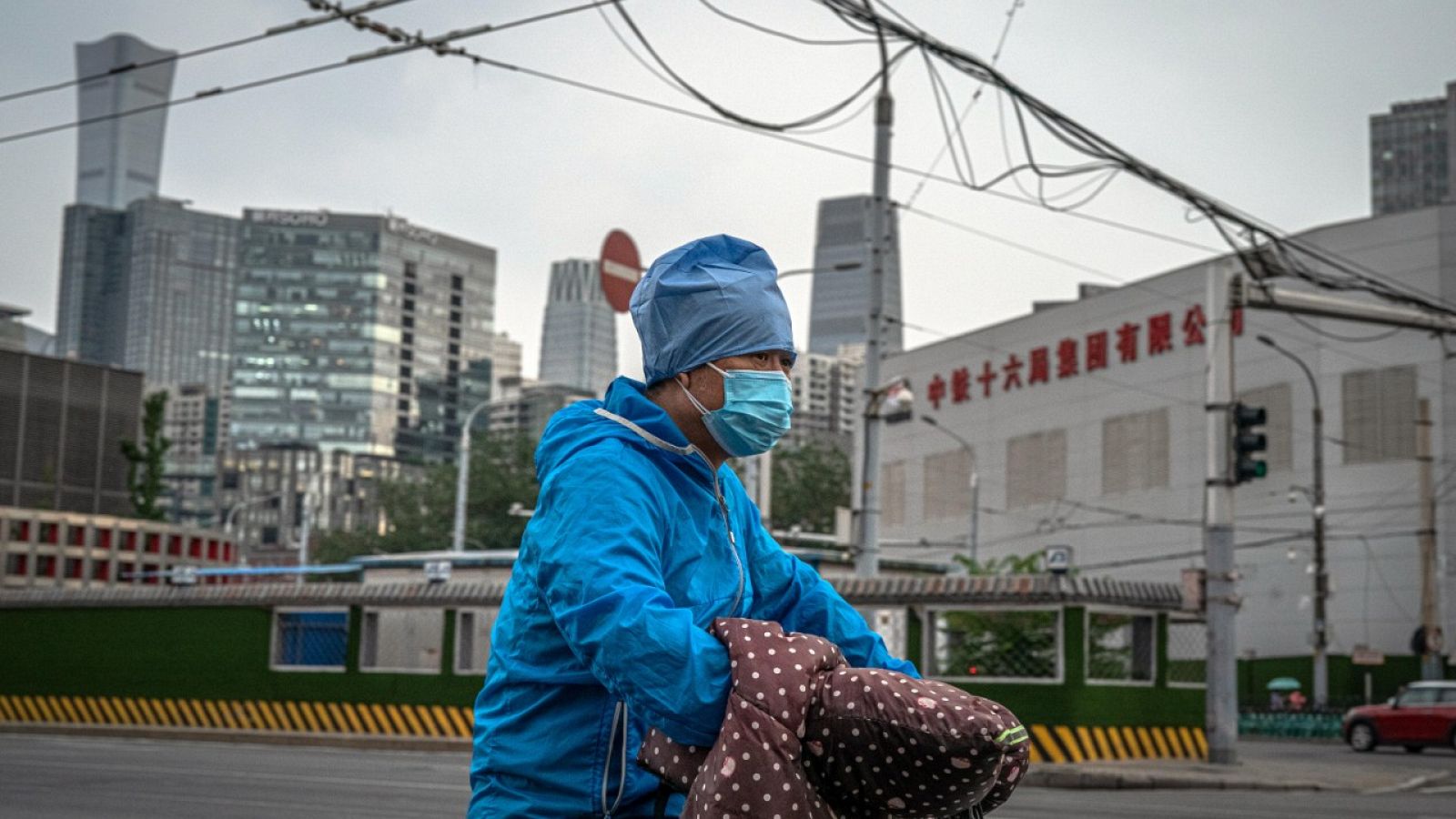 Un hombre con mascarilla montado sobre una moto en una calle de Pekín, China.