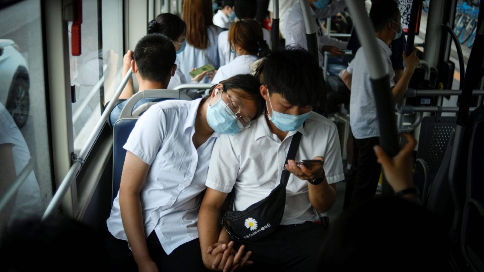 Una pareja con mascarilla viaja en un autobús en hora punta en Pekín