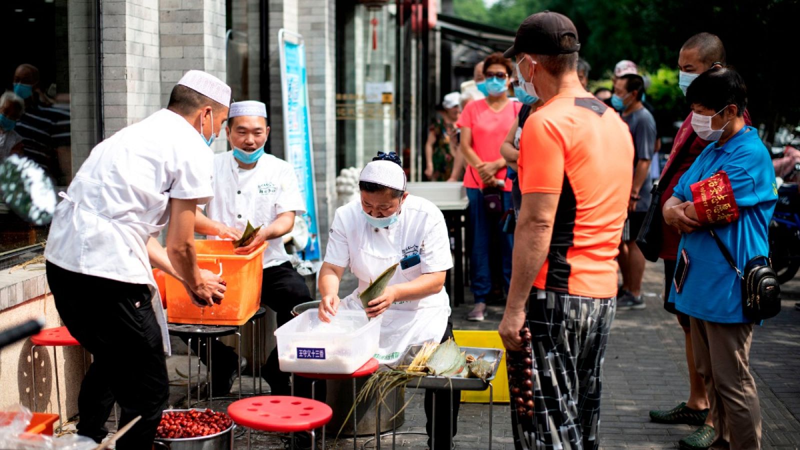 Trabajadores con mascarillas preparan comida en las calles de Pekín