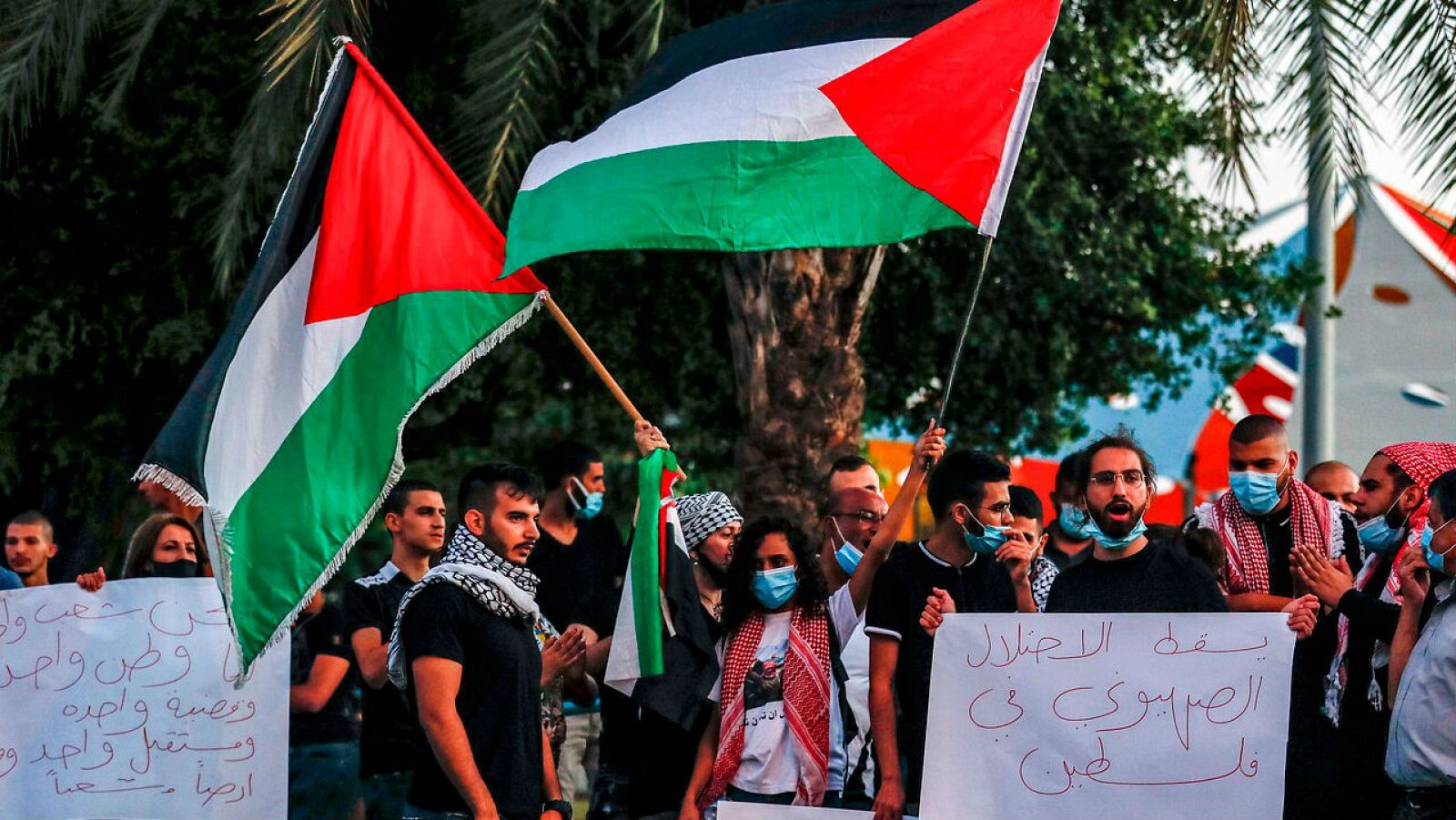 Los manifestantes, vestidos con máscaras debido a la pandemia del coronavirus COVID-19, ondean banderas palestinas mientras se reúnen para protestar contra los planes de Israel de anexionarse partes de Cisjordania.