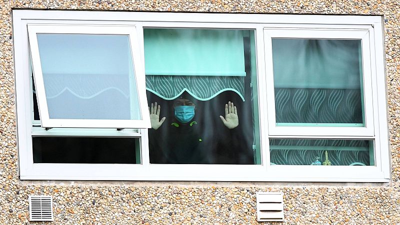 Un hombre confinado en el foco principal de Melbourne, en Australia, observa a través de una ventana