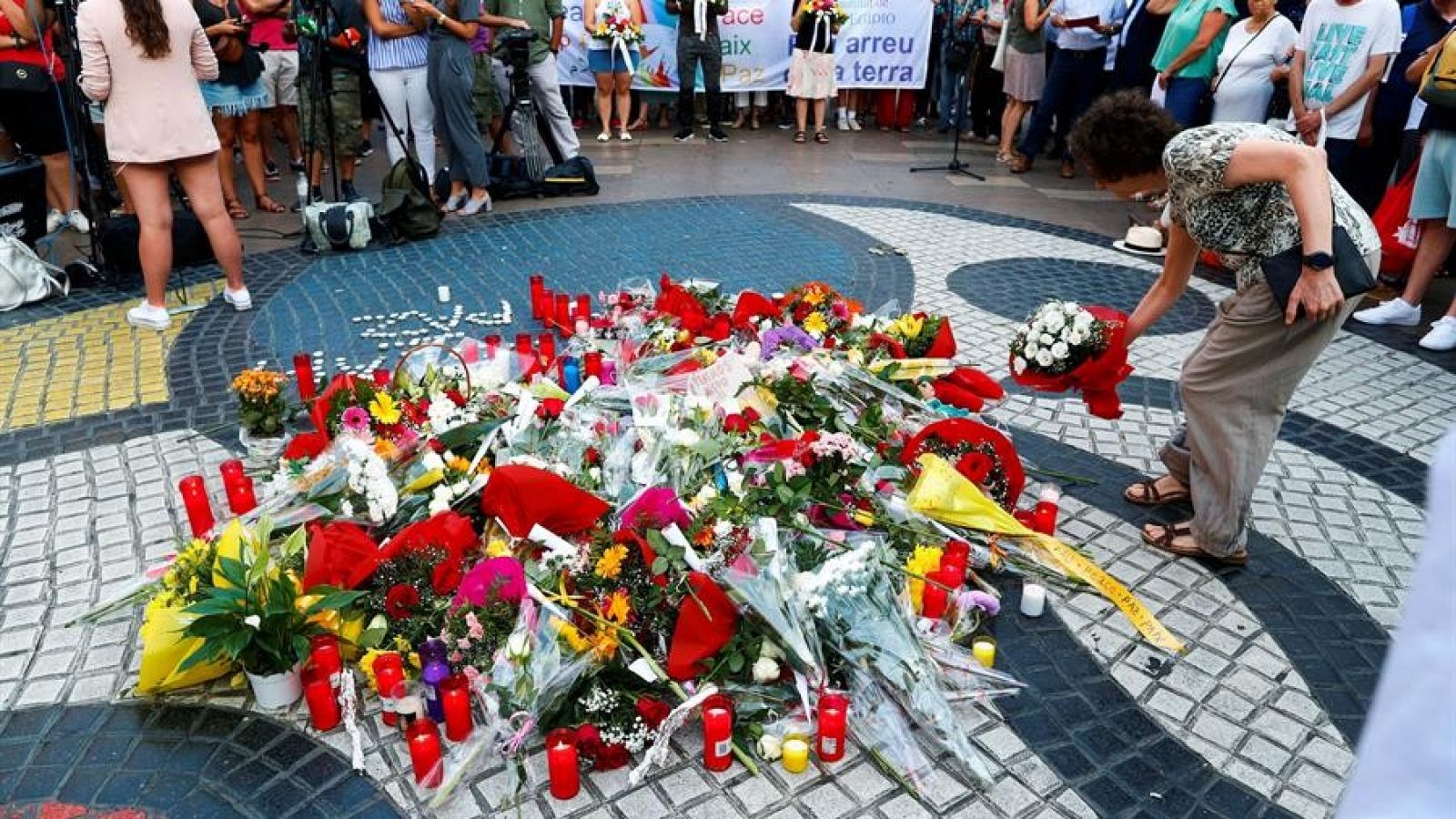 Una ciudadana deposita un ramo de flores en el mural de Miró de La Rambla de Barcelona en recuerdo de las víctimas en los atentados