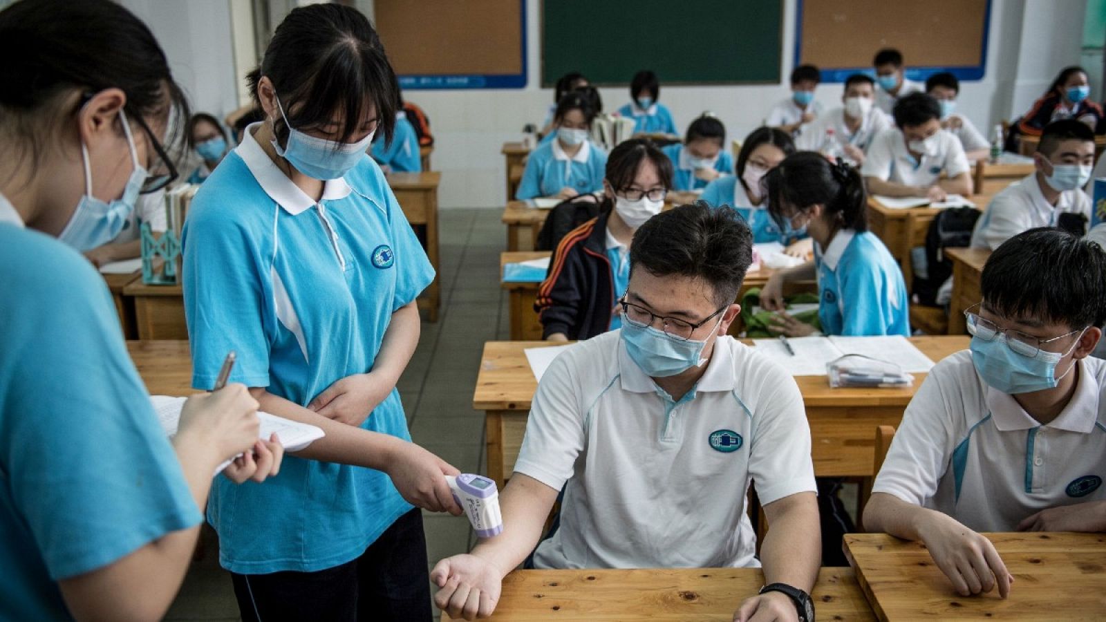 Dos estudiantes se toman la temperatura corporal en una escuela secundaria en Wuhan, donde se han retomado las clases esta semana.