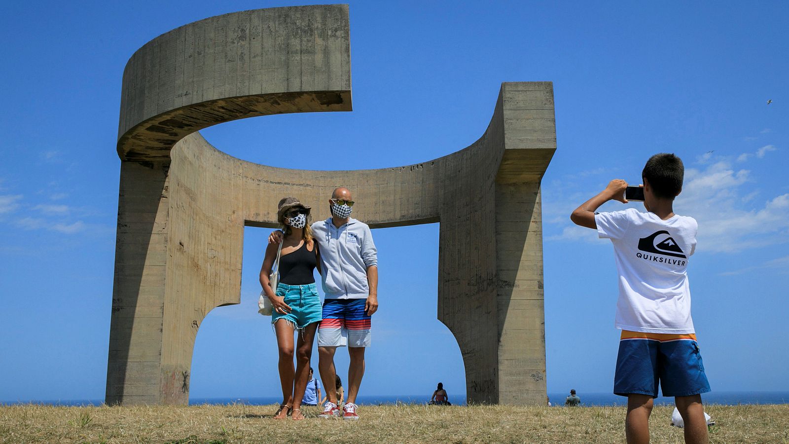 Dos turistas se fotografían ante el Elogio del Horizonte, de Eduardo Chillida, en Gijón.