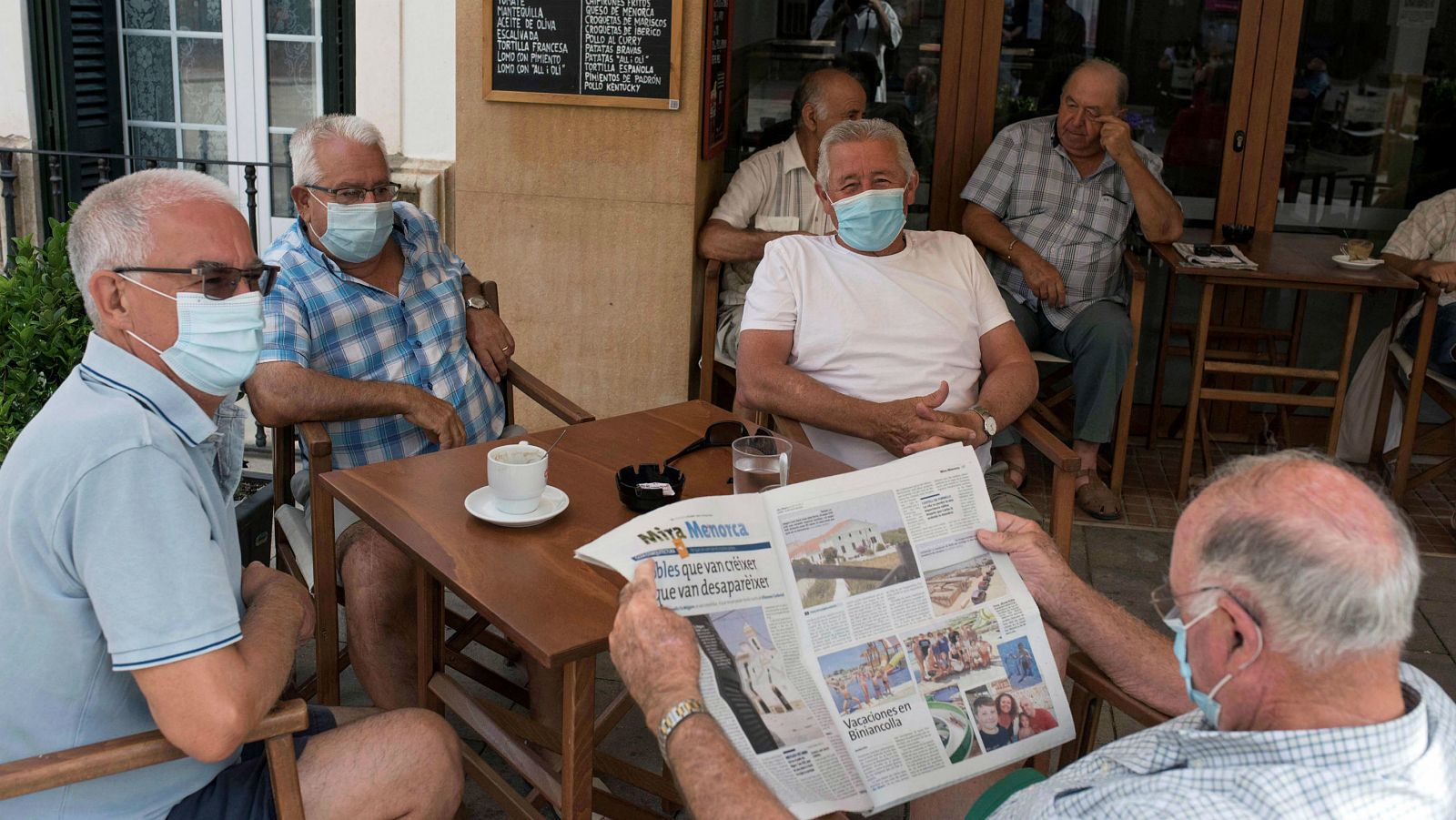 Un grupo de amigos con mascarilla desayuna en un bar de la localidad de Es Mercadal (Menorca) durante el primer día de obligatoriedad de la mascarilla en Baleares.