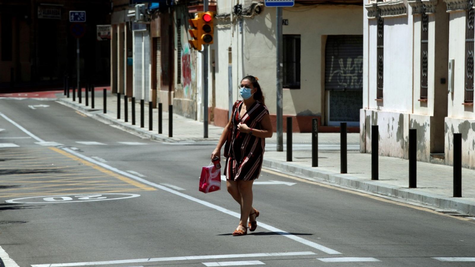 Una mujer con mascarilla pasea por una calle de Barcelona