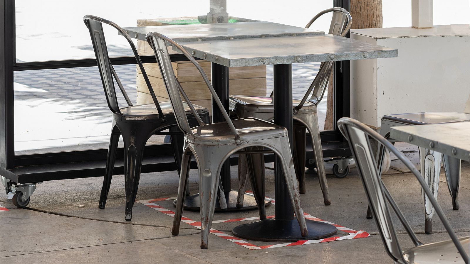 Sillas y mesas vacías en una terraza de bar con el suelo señalizado para mantener la distancia social.