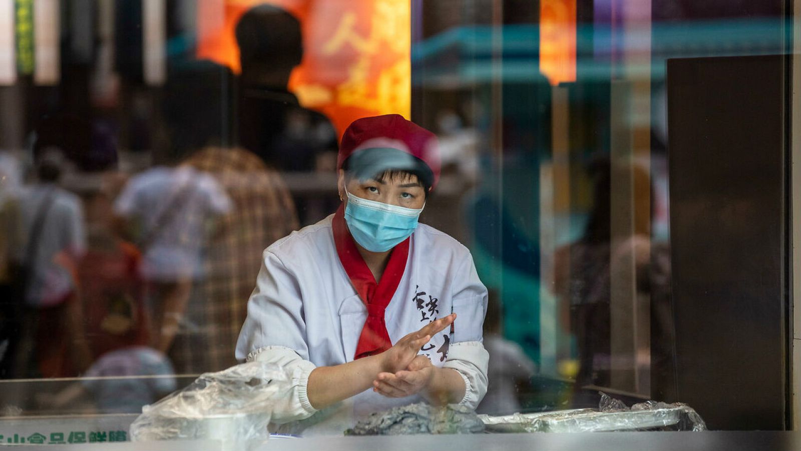 Una mujer con mascarilla hace bolas de masa en un escaparate en Shanghai, China.