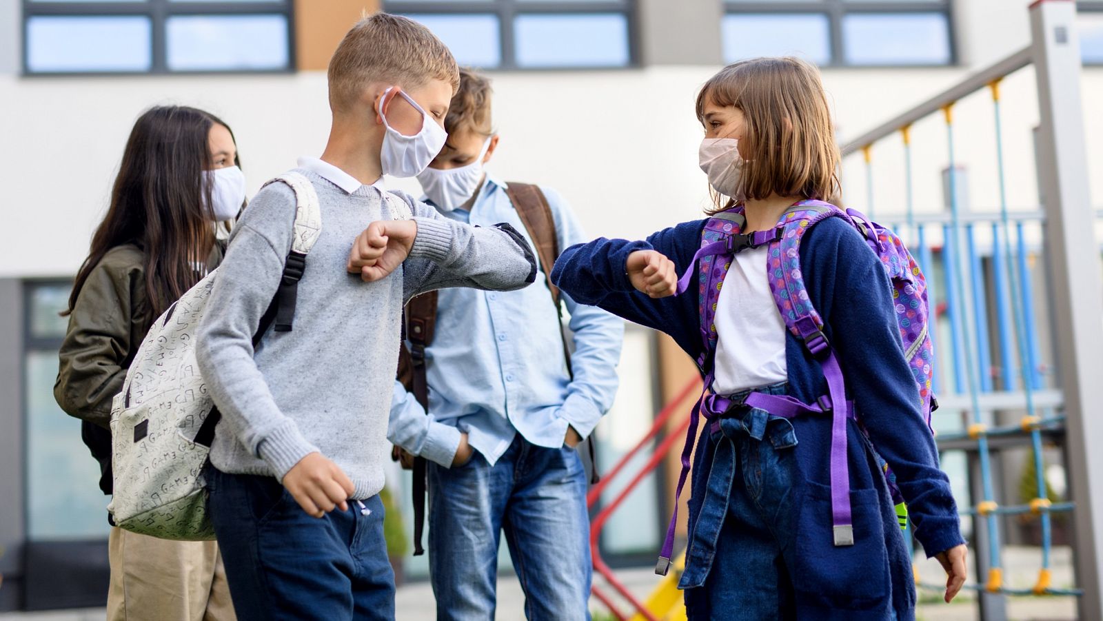 Dos niños se saludan con el codo en la puerta de un colegio en la vuelta al cole tras el confinamiento por el coronavirus.