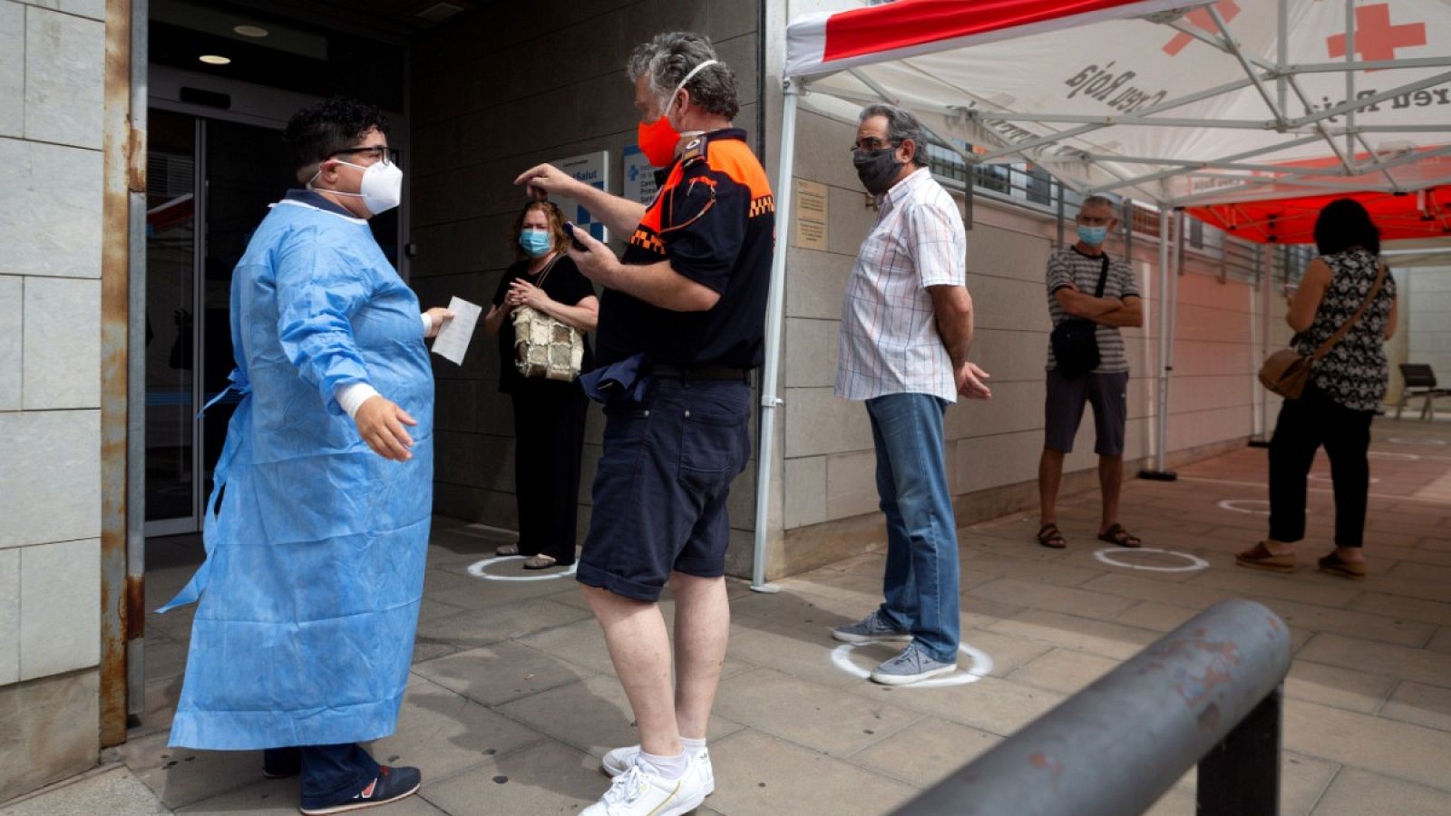 Un hombre habla con un sanitario a las puertas de un centro médico en Santa Coloma de Gramanet, Barcelona.