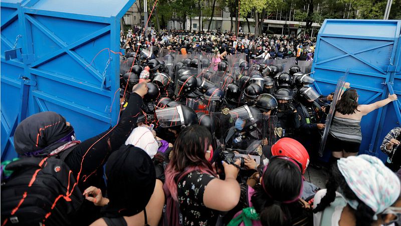 Manifestantes intentan romper una barricada mientras intentan marchar hacia un monumento durante una marcha exigiendo justicia para las víctimas de violencia de género y feminicidios en la Ciudad de México, México
