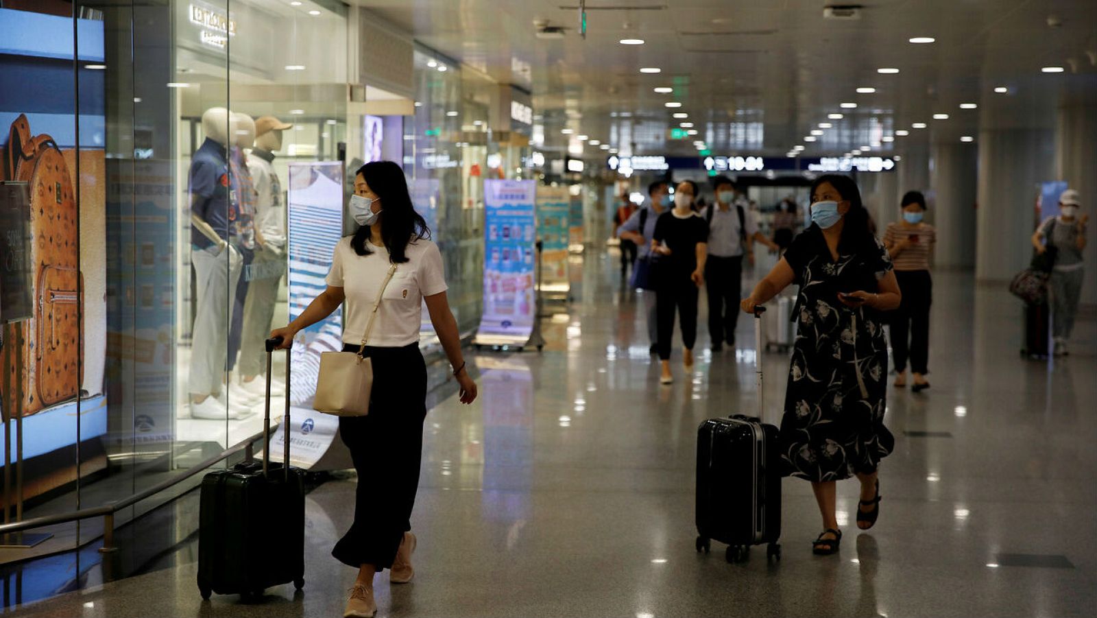 Viajeros con mascarillas pasan por las tiendas minoristas en el Aeropuerto Internacional de Beijing Capital en Beijing, China.