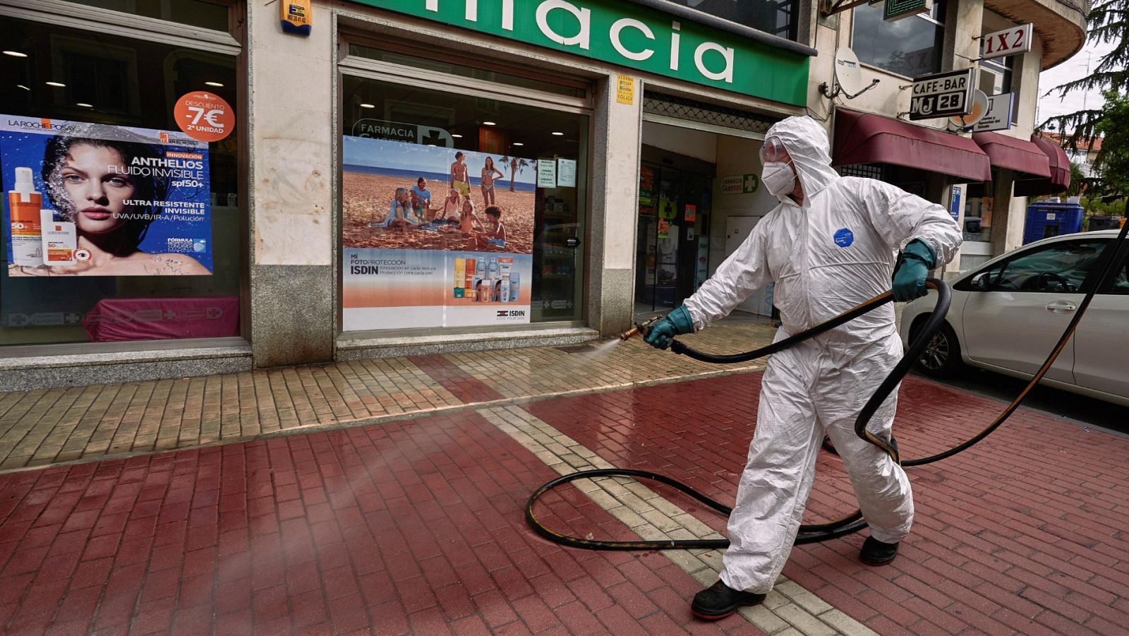 Un operario desinfecta la entrada de una farmacia en una calle de Ávila