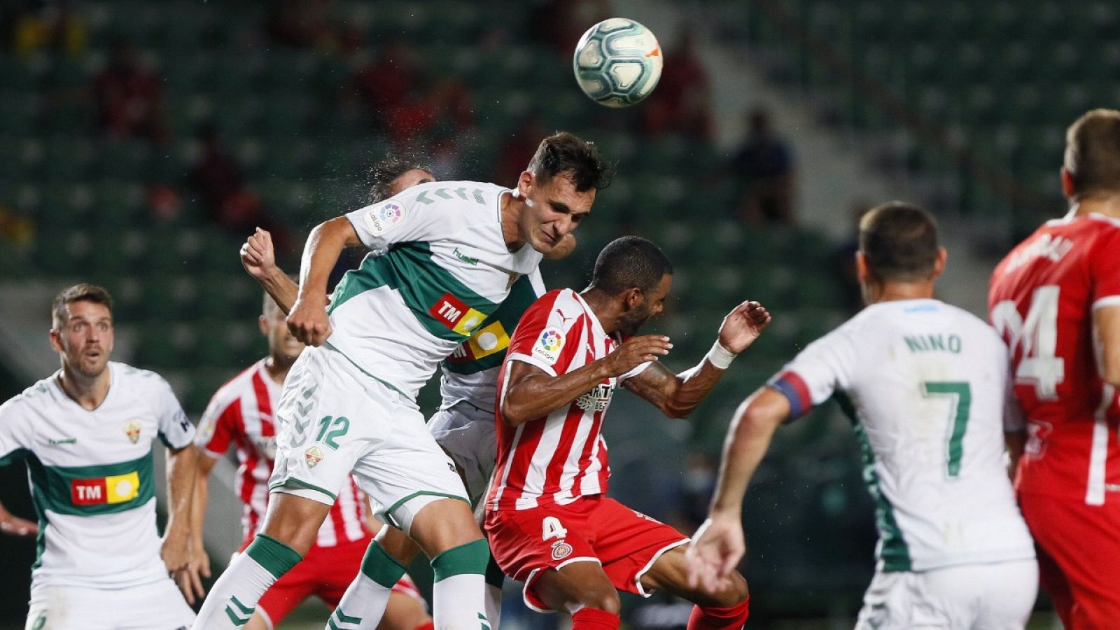 El defensa del Elche Dani Calvo (i) salta por el balón con Jonás Ramalho, del Girona.