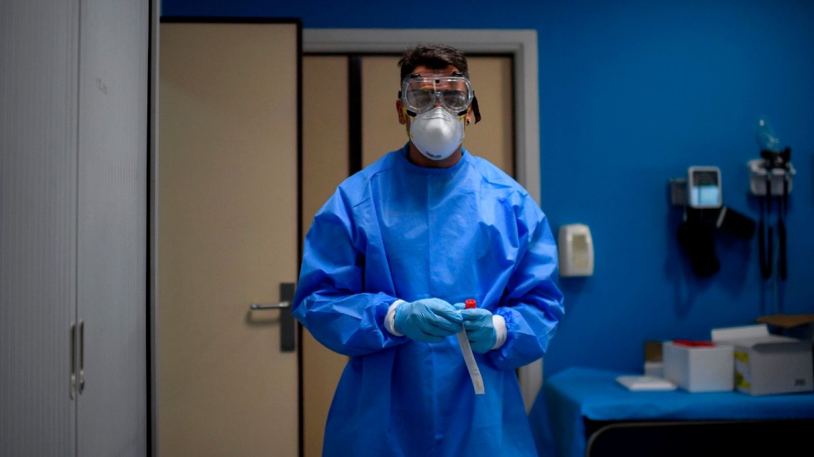 Un sanitario, con equipo de protección, sostiene una muestra en un centro de pruebas en Madrid, este agosto.
