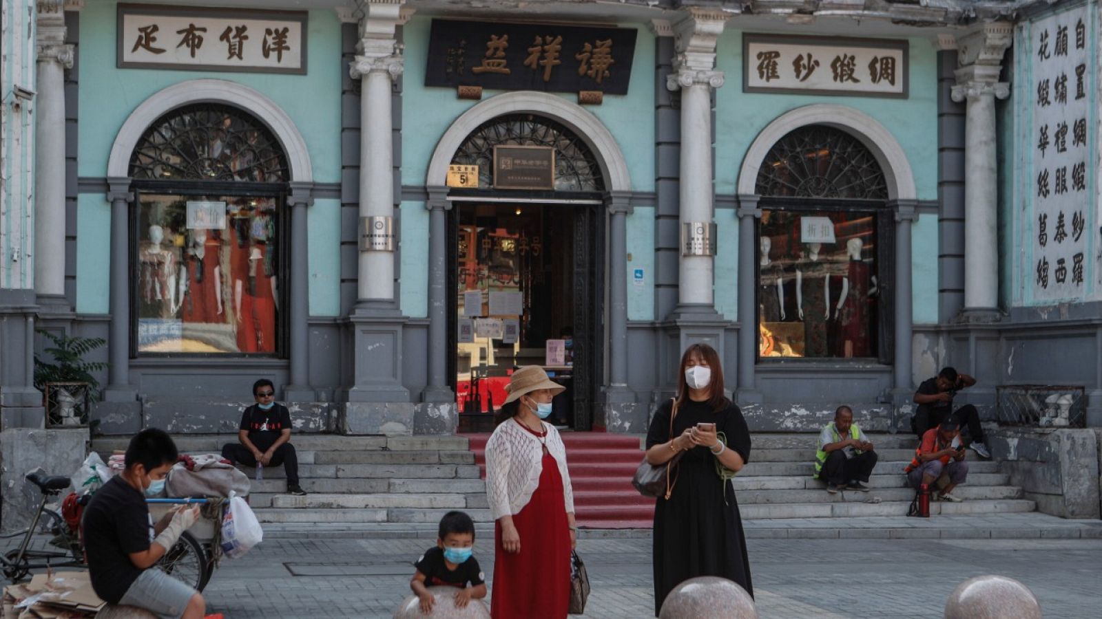 Varias personas con mascarilla en una calle comercial de Pekín.