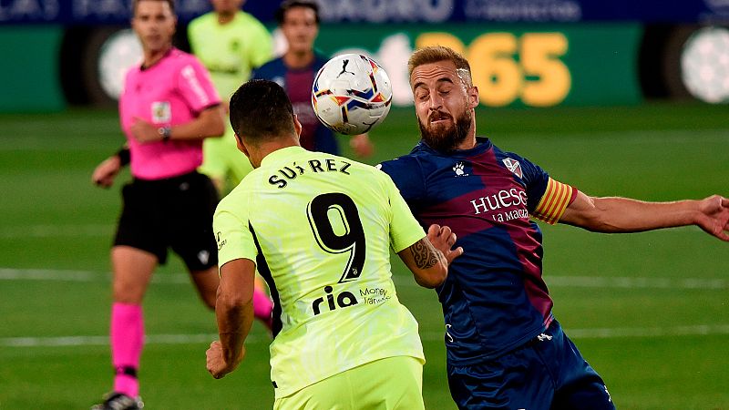 El delantero del Atlético de Madrid Luis Suárez (i) lucha con Jorge Pulido, de la SD Huesca