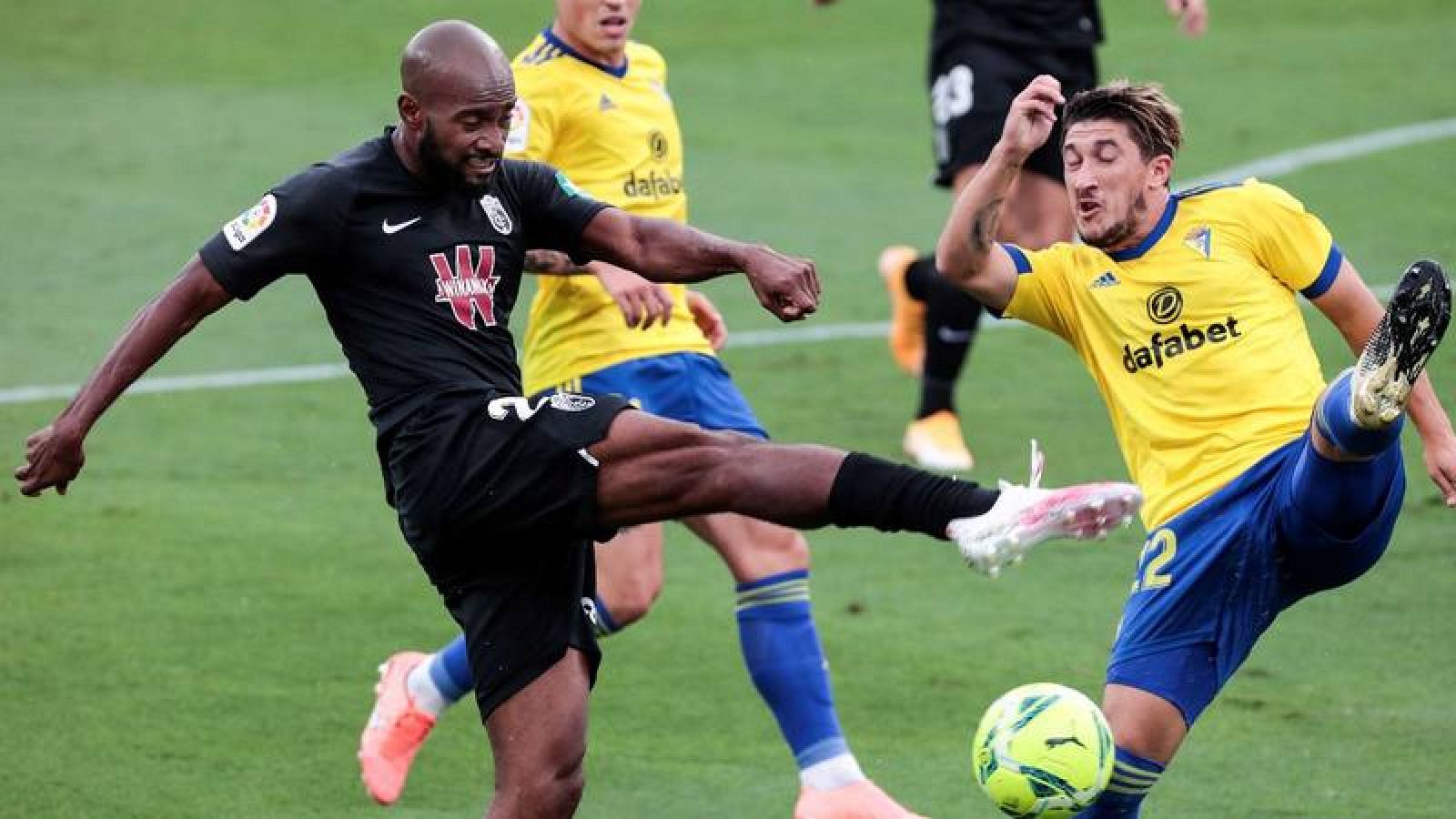 El defensa francés del Granada CF, Dimitri Foulquier (i) pelea un balón con el defensa del Cádiz Luis Espino. 